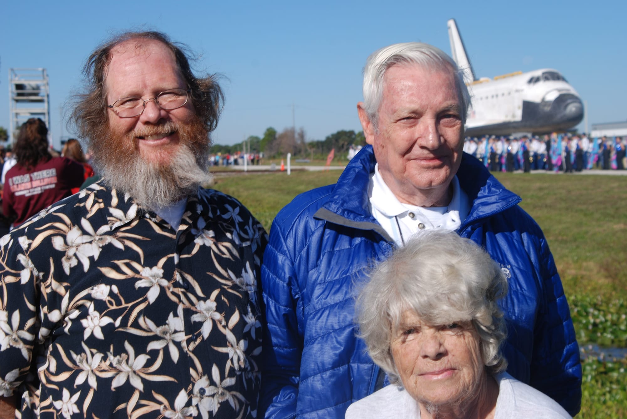 Two men and a short woman with the space shuttle behind them