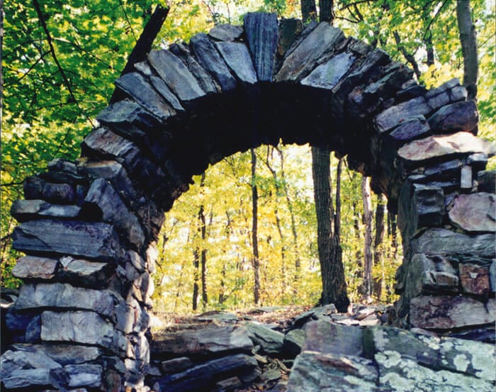 Stone arch like a portal into a forest