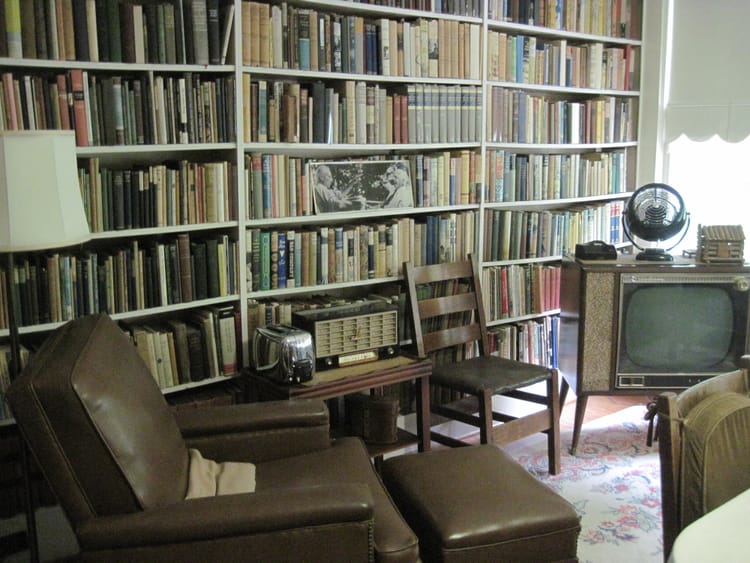 A living room straight out of the early 1950s with a wall of books, radio, TV, and toaster